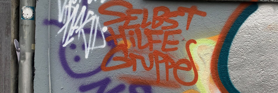 Ein Graffiti auf dem "Selbsthilfegruppe" steht